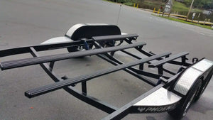 Black metal car trailer frame with dual axles and fenders.